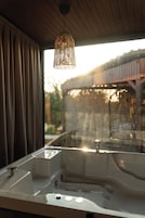 A bathroom with a large bathtub, a sink, and a hanging light fixture.