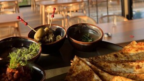 A restaurant with a wooden interior, large windows, and a variety of dishes including pizza and bowls of food.