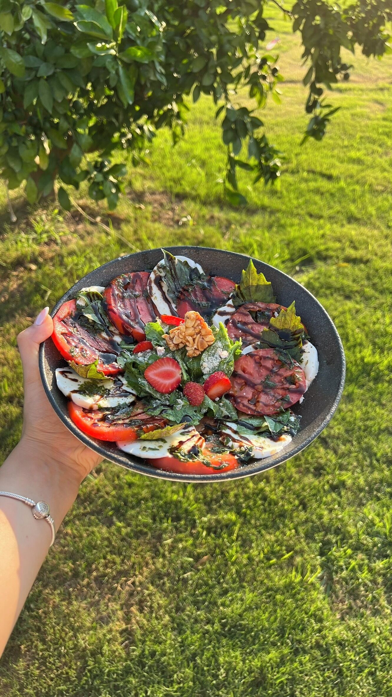 A person holding a plate of food outdoors.
