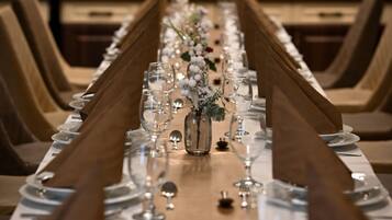 A long dining table set with multiple chairs, a vase with flowers, and a wooden table runner.