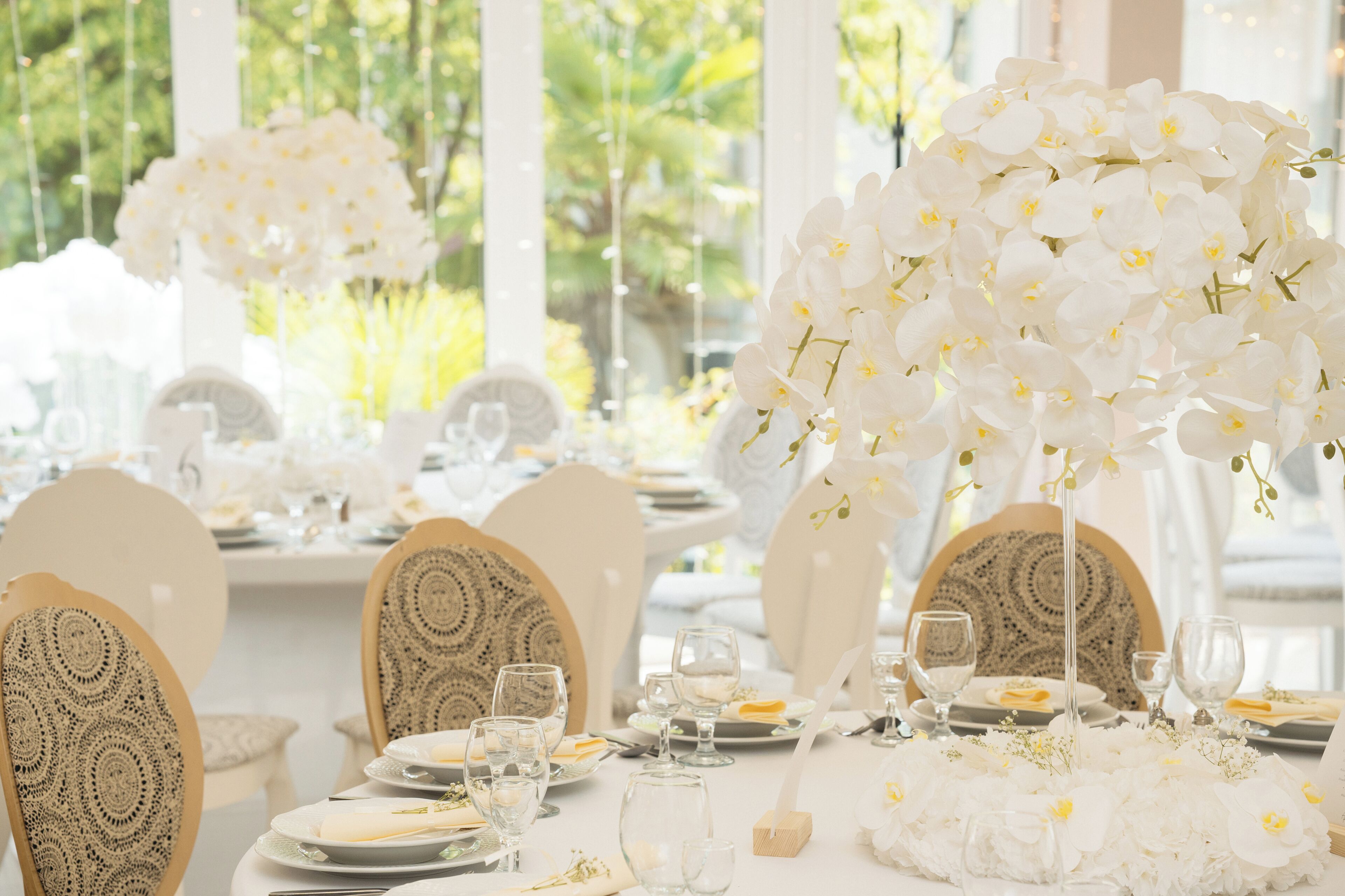 A table set with white flowers, clear glassware, and patterned chairs.