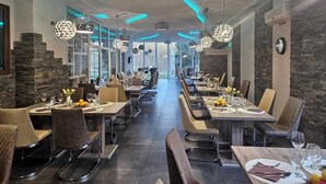 Un restaurante moderno con mesas largas, sillas, y lámparas esféricas colgantes.