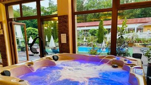 Un jacuzzi con vistas a una piscina y una zona de estar al aire libre.