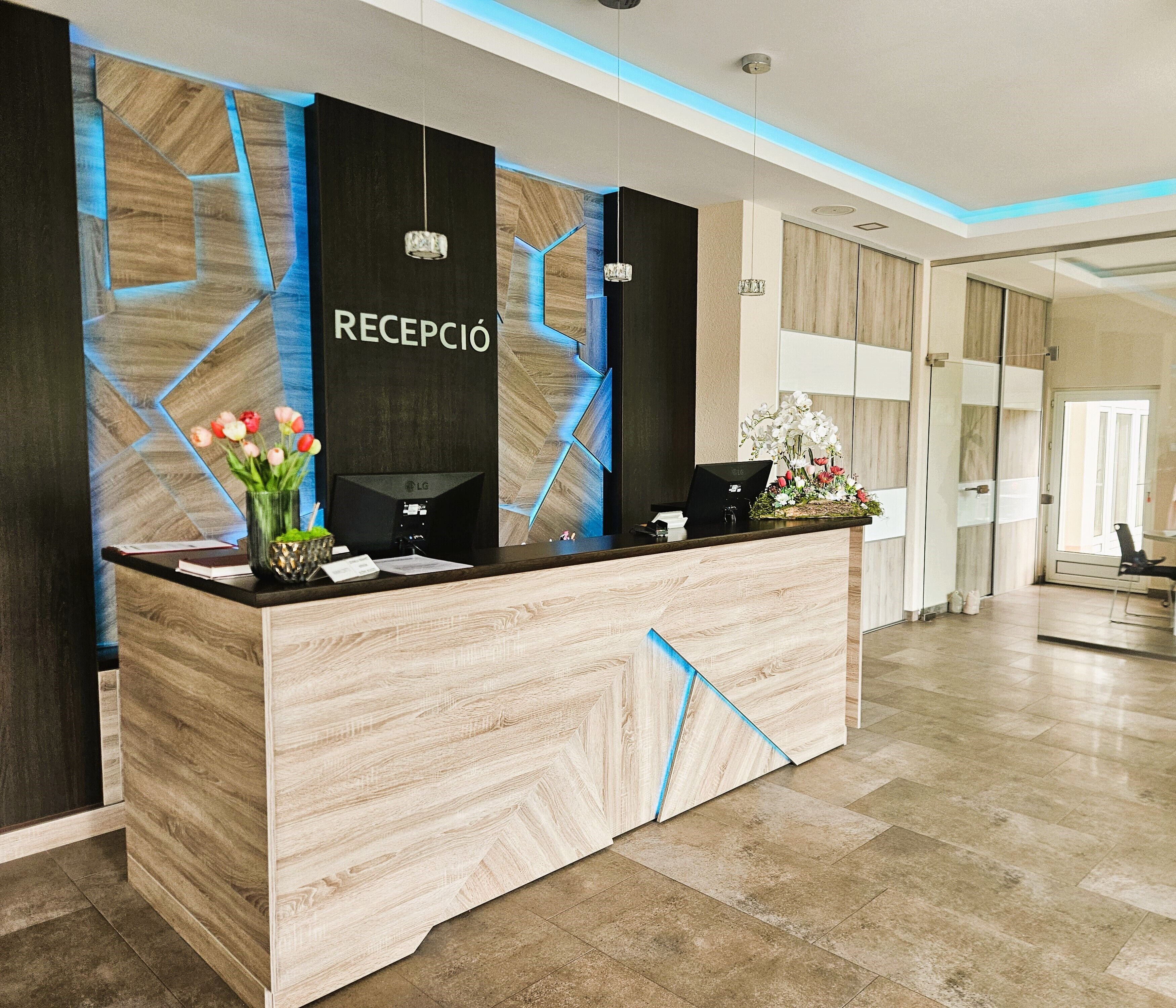 Un mostrador de recepción de diseño moderno, un cartel que dice 'RECEPCIÓN' y un jarrón con flores.