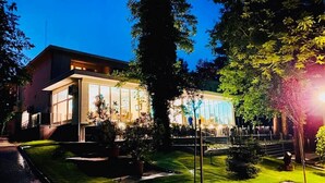 Un edificio moderno con grandes ventanales y un jardín cuidado, de noche.