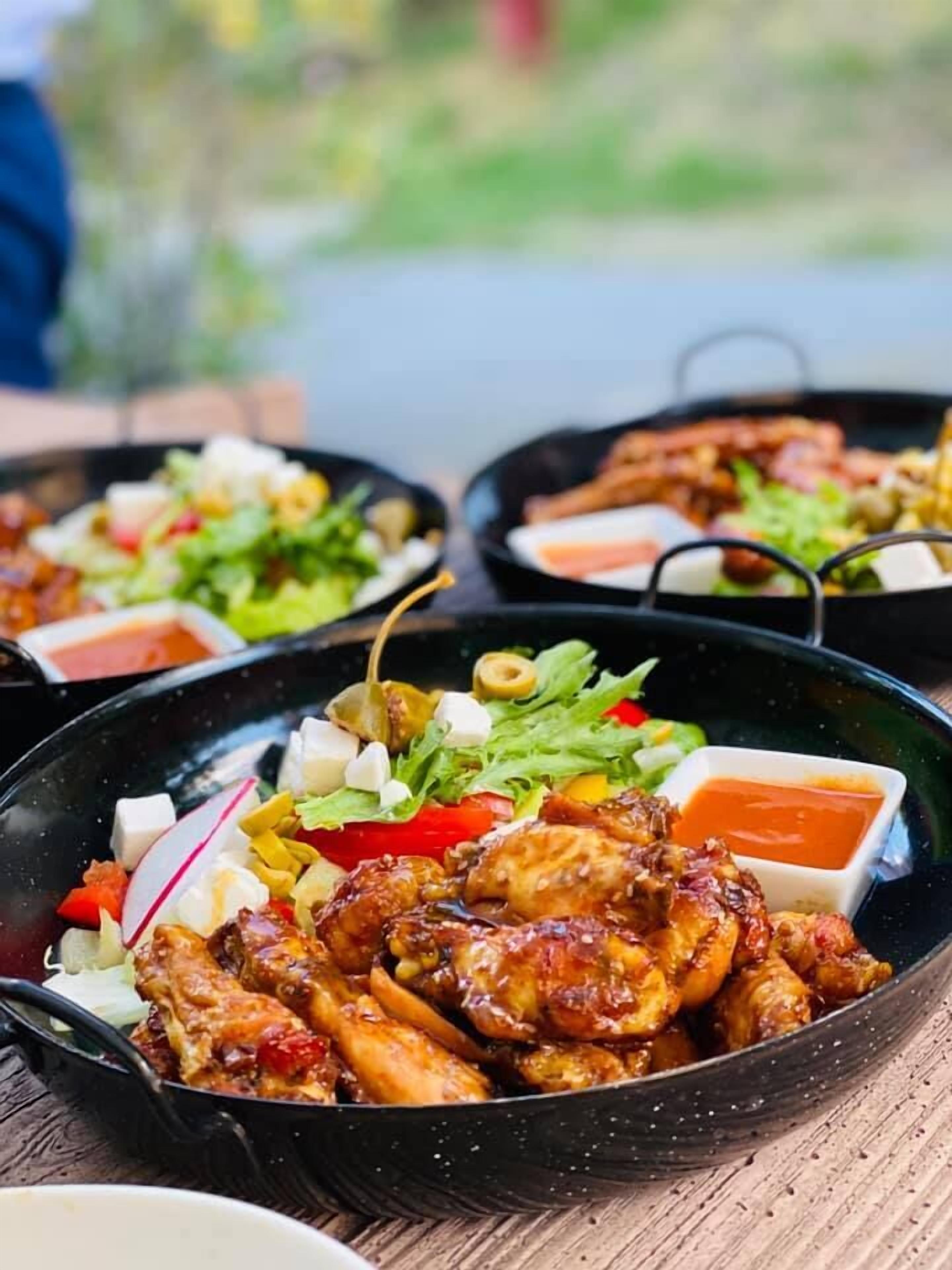 A meal with chicken wings, a salad, and a dipping sauce on a table.