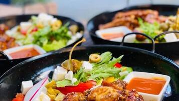 A meal with chicken wings, a salad, and a dipping sauce on a table.