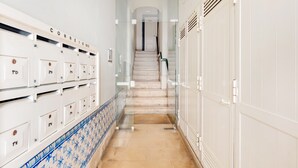 Ein Hotelkorridor mit Schließfächern links, einer Treppe in der Mitte und einer Tür am Ende.