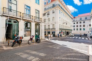 Une vue de rue avec des immeubles, un passage piéton et des motos garées.