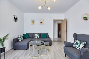A modern living room with a grey sofa, two round tables, and a chandelier.