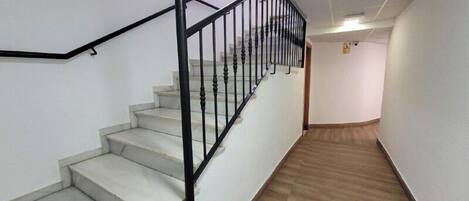 A staircase with black railings leading to a landing with a wooden floor.