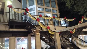 A staircase with black railings, decorated with red roses and string lights. - Large Mediterranean pool, river, basketball, sleeps 26, 8 bedrooms (seguin)