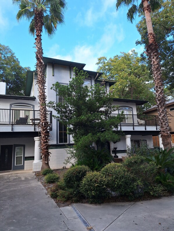 A two-story building with a balcony and a well-maintained garden.