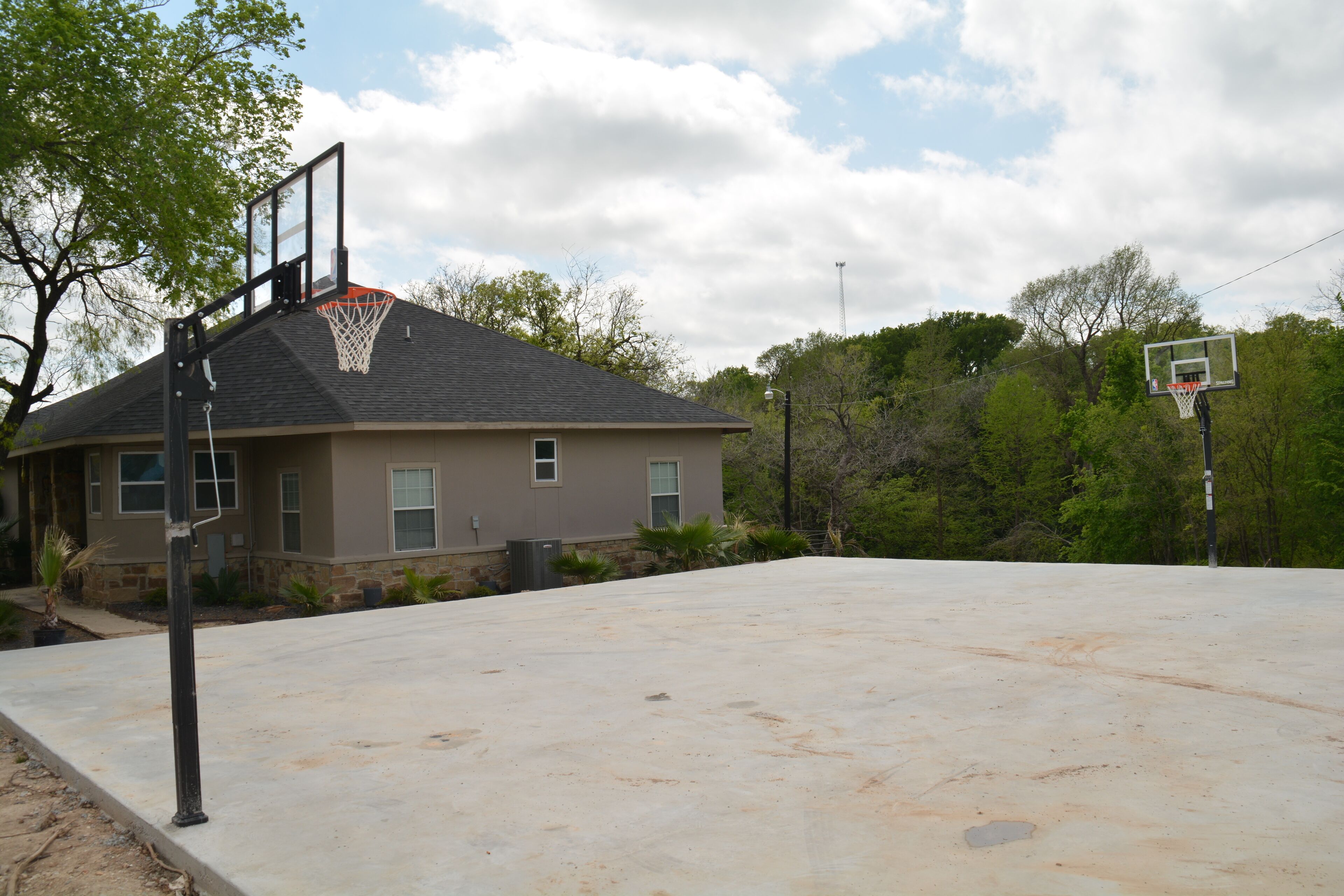 An outdoor basketball court with a house in the background.