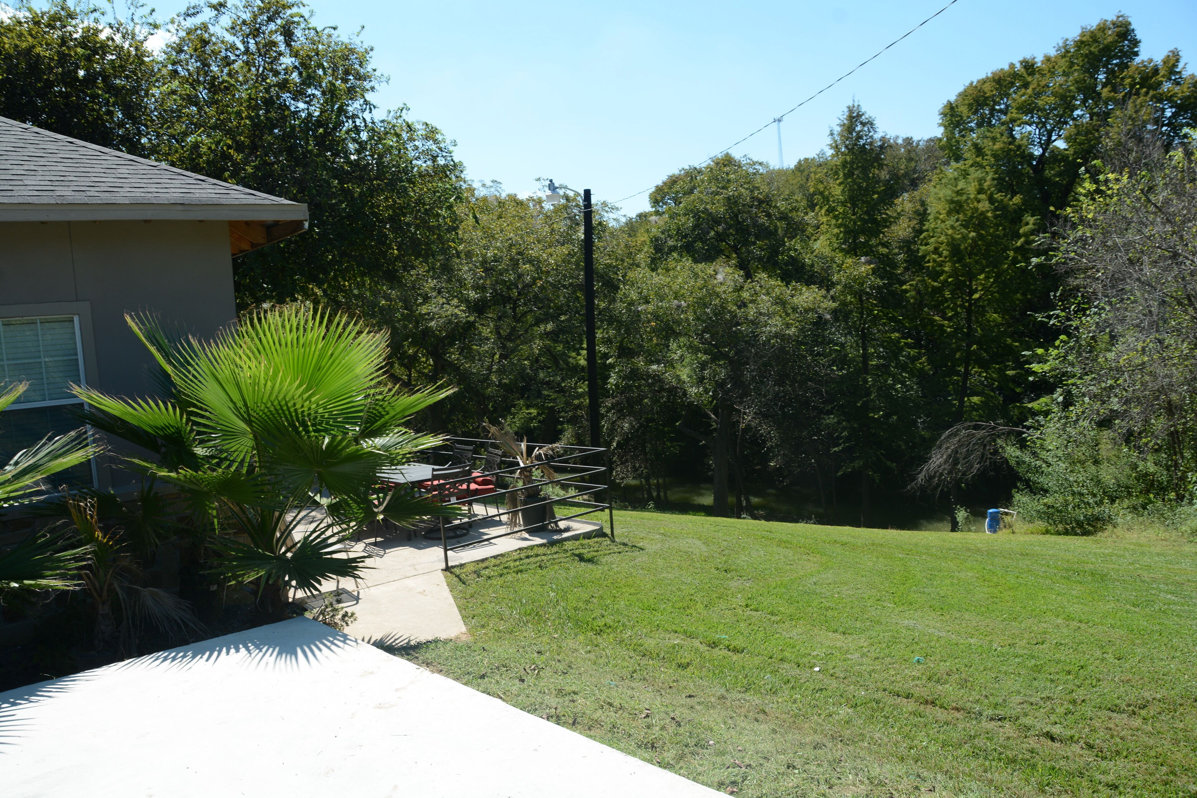 A residential property with a well-maintained lawn, a patio area with outdoor furniture, and a house with a sloped roof.
