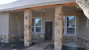 A house with a stone facade, a front door, and two windows with white frames.