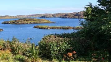 A coastal landscape with a clear view of a bay, several small islands, and lush greenery.
