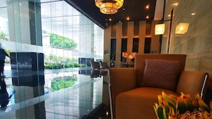 A modern lobby with a glass wall, a central seating area, and a decorative plant. - One Bedroom Balcony With Great Location and Value (Makati)