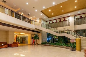 A spacious lobby with a curved staircase, seating areas, and a reception desk. - Crystal Hotel (Boluo)