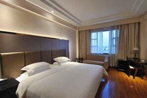 A hotel room with a large bed, a sofa, a desk, and a view of the city. - Crystal Hotel (Boluo)