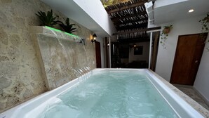 A spa area with a large hot tub, stone walls, and a wooden ceiling. - Casa Moneda 5br old City AC Picusi (Bolívar)