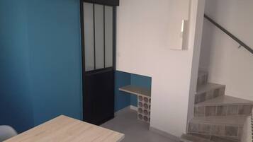 A room with a wooden table, a black door, a white wall, a blue accent wall, and a staircase.