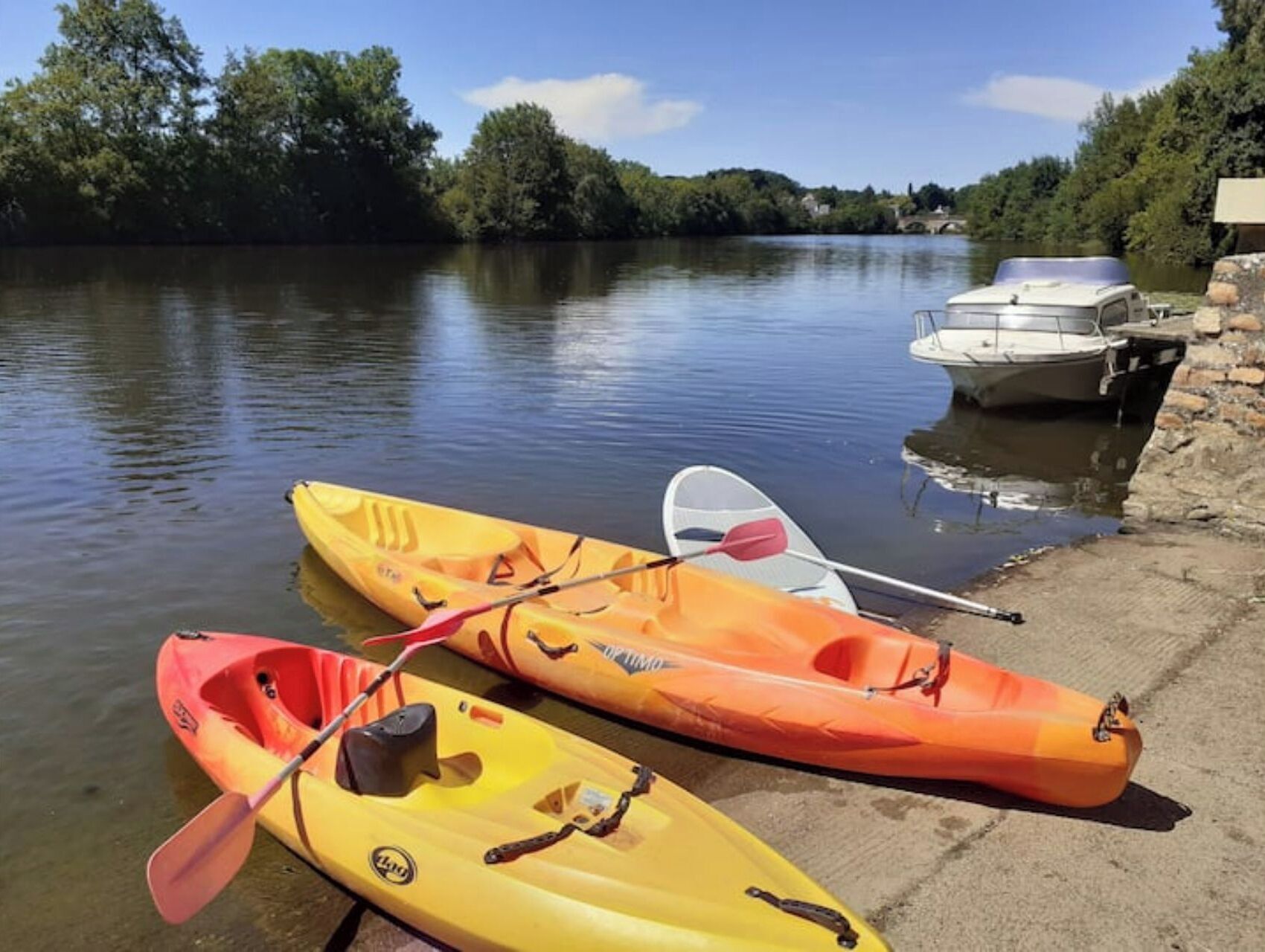 Two kayaks on a dock with a calm river and trees in the background.