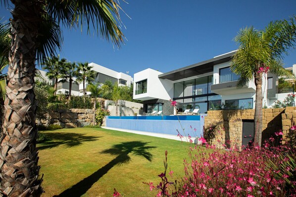 Una casa moderna con pared de piedra, valla azul y césped bien cuidado.