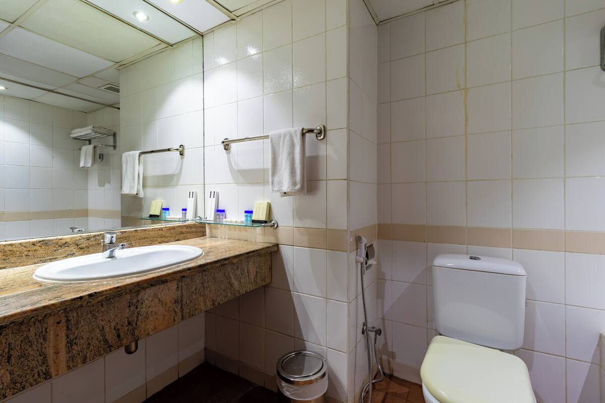 A bathroom with a sink, mirror, towel rack, toilet, and shower.