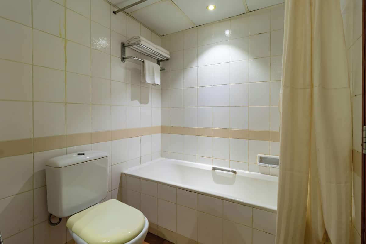 A bathroom with a toilet, bathtub, and a towel rack.