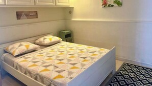 A bedroom with a bed, pillows, a nightstand, a wall-mounted lamp, and a framed picture. - Deux Pièces Avec Terrasse et Parking au Calme (Cagnes-sur-Mer)