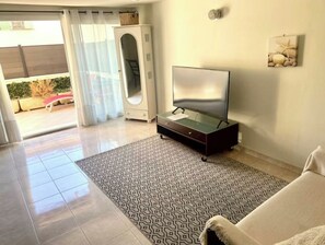 Una sala de estar moderna con una televisión de pantalla plana sobre un mueble bajo, un tapete estampado y un sofá.