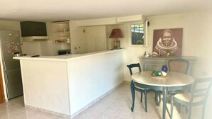 A compact kitchen with a central island, a dining table with chairs, and a small cabinet. - Deux Pièces Avec Terrasse et Parking au Calme (Cagnes-sur-Mer)