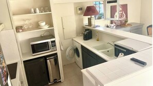 A compact kitchen with a microwave, washing machine, and a small refrigerator. - Deux Pièces Avec Terrasse et Parking au Calme (Cagnes-sur-Mer)