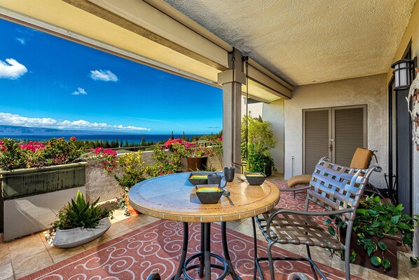 A round table with chairs and a view of the ocean.