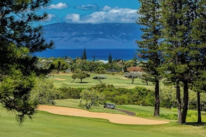 Ein Golfplatz mit Blick auf das Meer und die Berge im Hintergrund.