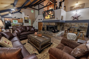 Una sala de estar acogedora con sofás de cuero, una chimenea y una cocina al fondo.