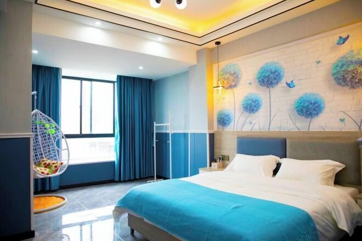 A modern bedroom with a large bed, a hanging chair, and a mural on the wall.