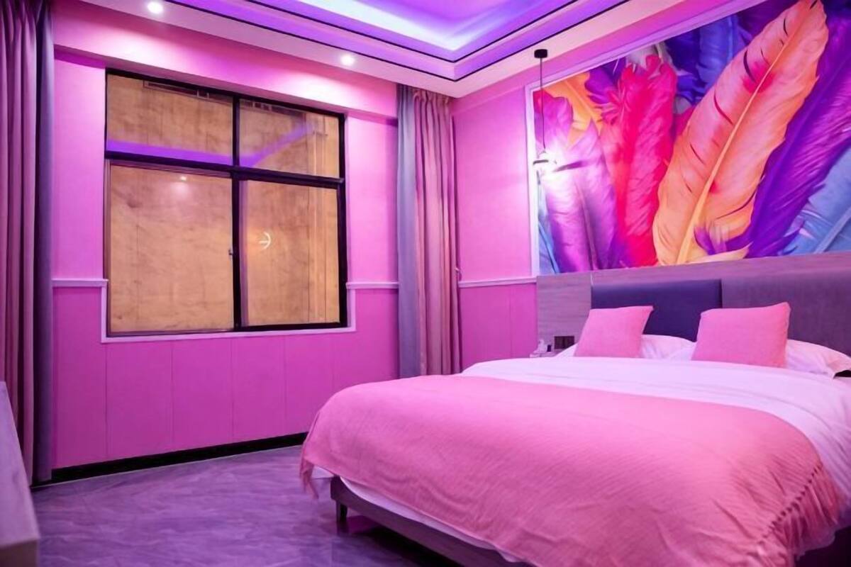 A bedroom with a bed, curtains, a window, and a wall mural.