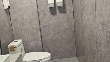 A bathroom with a white toilet, a towel dispenser, and a wall-mounted towel rack.