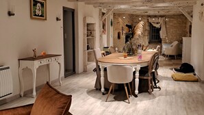 A dining area with a round wooden table, white chairs, and a rustic stone wall. - Typical house with dovecote, swimming pool, summer kitchen, close to vineyards (Courrech, GREZELS)