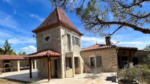 A stone building with a red-tiled roof, a small tower, and a covered patio area with outdoor furniture. - Typical house with dovecote, swimming pool, summer kitchen, close to vineyards (Courrech, GREZELS)
