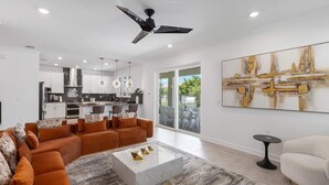 A spacious living room with a sofa set, a coffee table, and a dining area with chairs. - Sunshine Shores | Beach-facing Stunner w/ Sunny PVT Pool, Fairytale BR, Karaoke (Melbourne Beach)