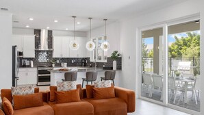 A modern kitchen with white cabinets, a central island, and pendant lighting. - Sunshine Shores | Beach-facing Stunner w/ Sunny PVT Pool, Fairytale BR, Karaoke (Melbourne Beach)