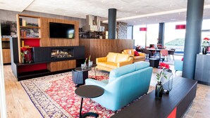 A modern living room with a fireplace, a flat-screen TV, and a sofa. - Bastion Hotel Amersfoort (Amersfoort)
