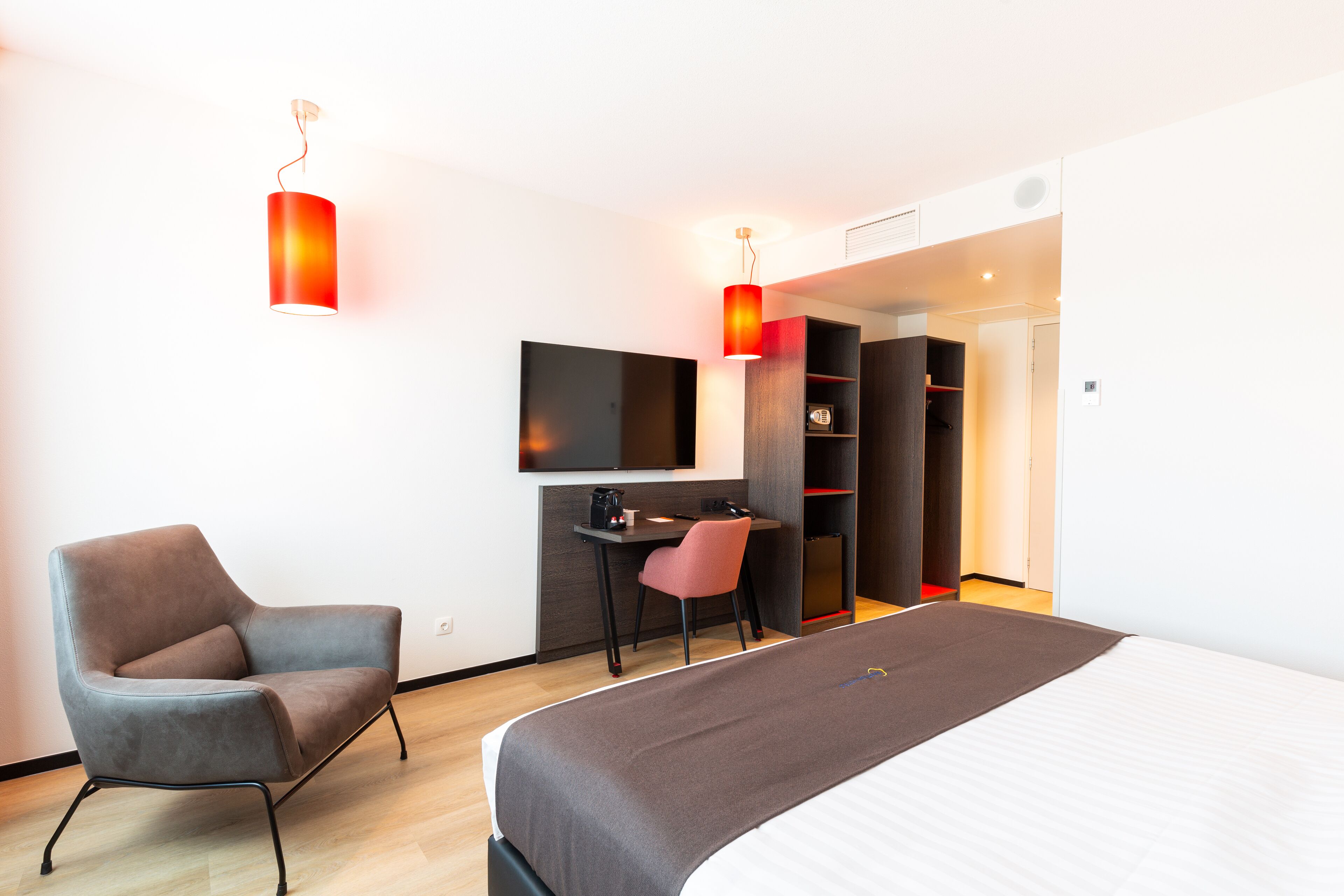 Una habitación de hotel moderna con una cama, un escritorio, una silla y un televisor.