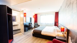 A modern hotel room with a bed, a desk, a chair, and a TV. - Bastion Hotel Amersfoort (Amersfoort)