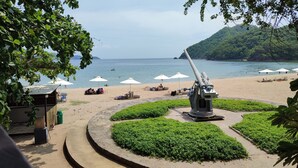 Een strand met een grote kanon, ligbedden en parasols.
