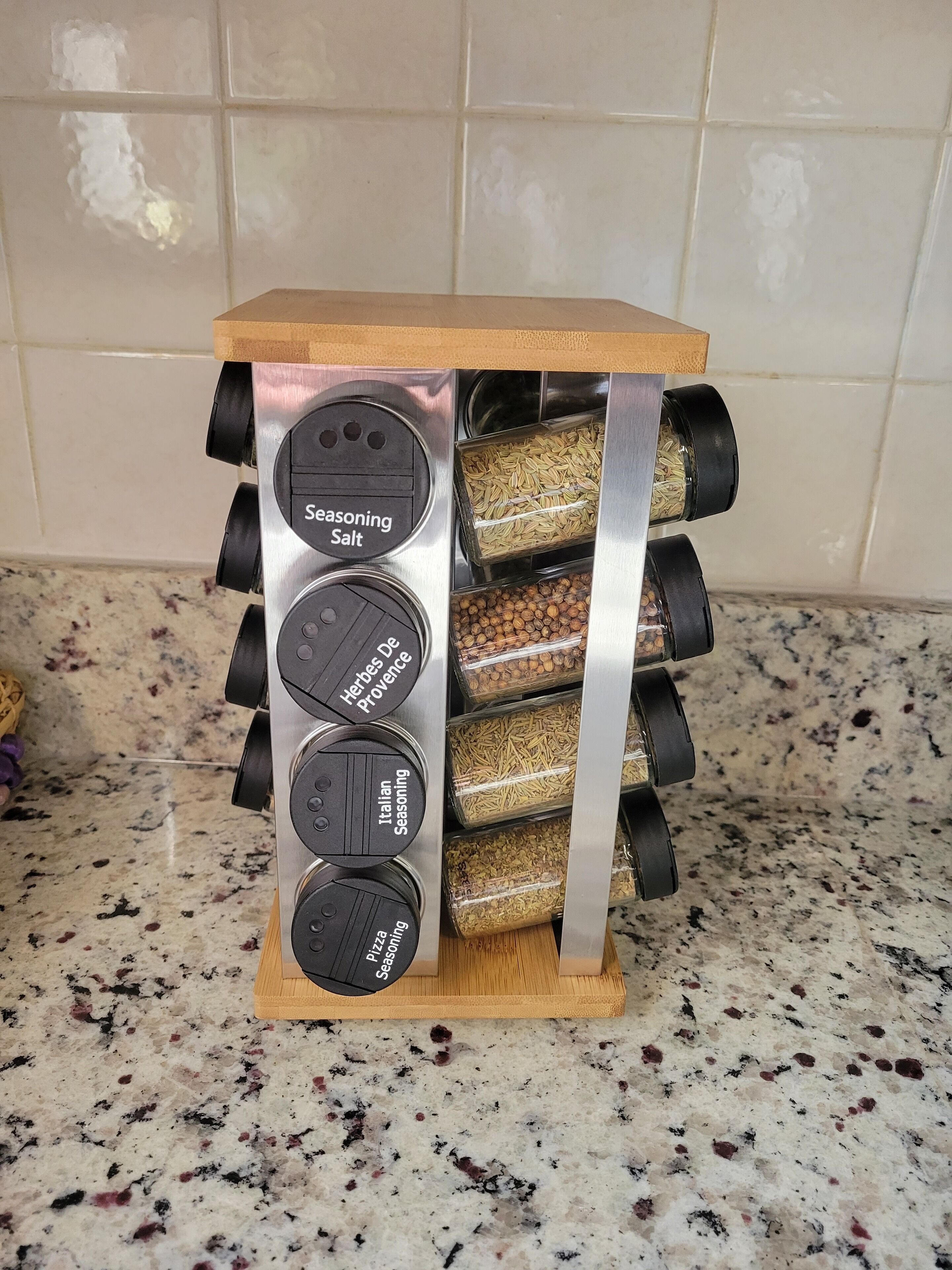 A spice rack with labeled containers for seasoning salt, herbs de provence, italian seasoning, and pizza seasoning.