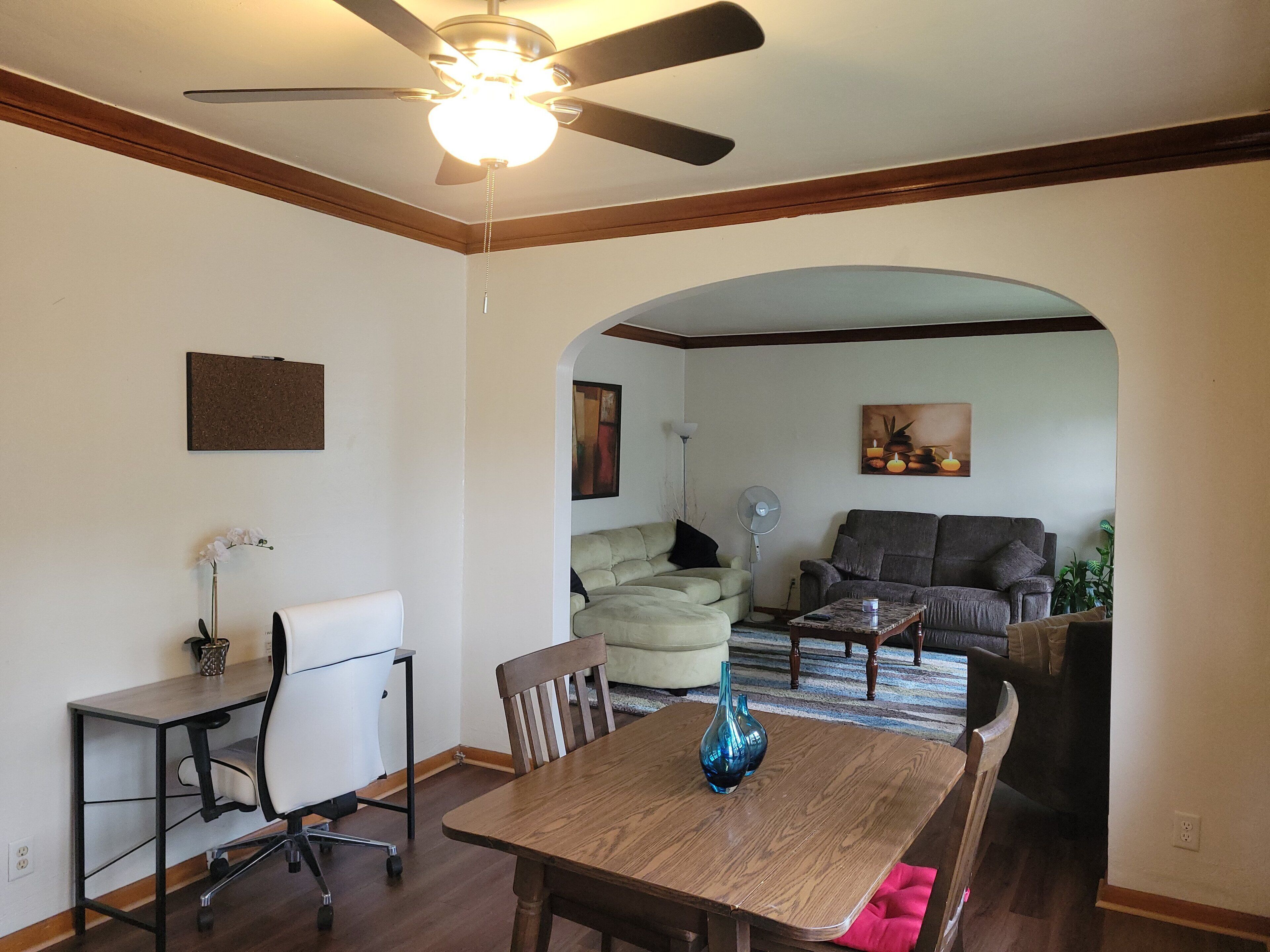 A dining area with a table and chairs, a ceiling fan, and a painting on the wall.